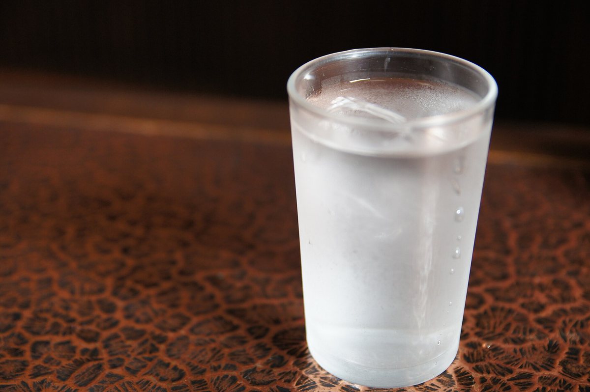 冷たい水の入ったコップ。外側が白くくもり、小さな水滴がついている