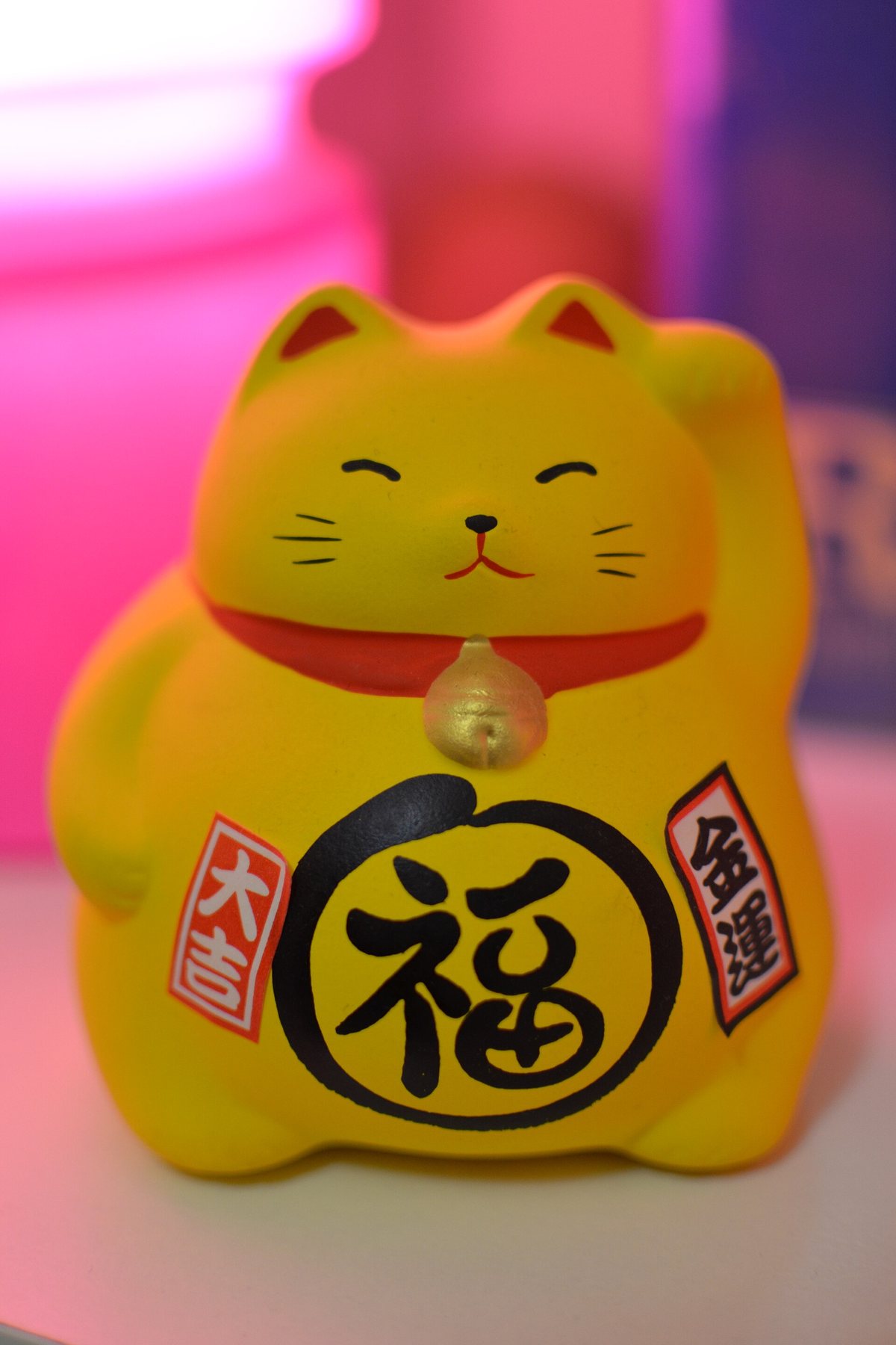 片方の前足をあげている、黄色い招き猫の置物