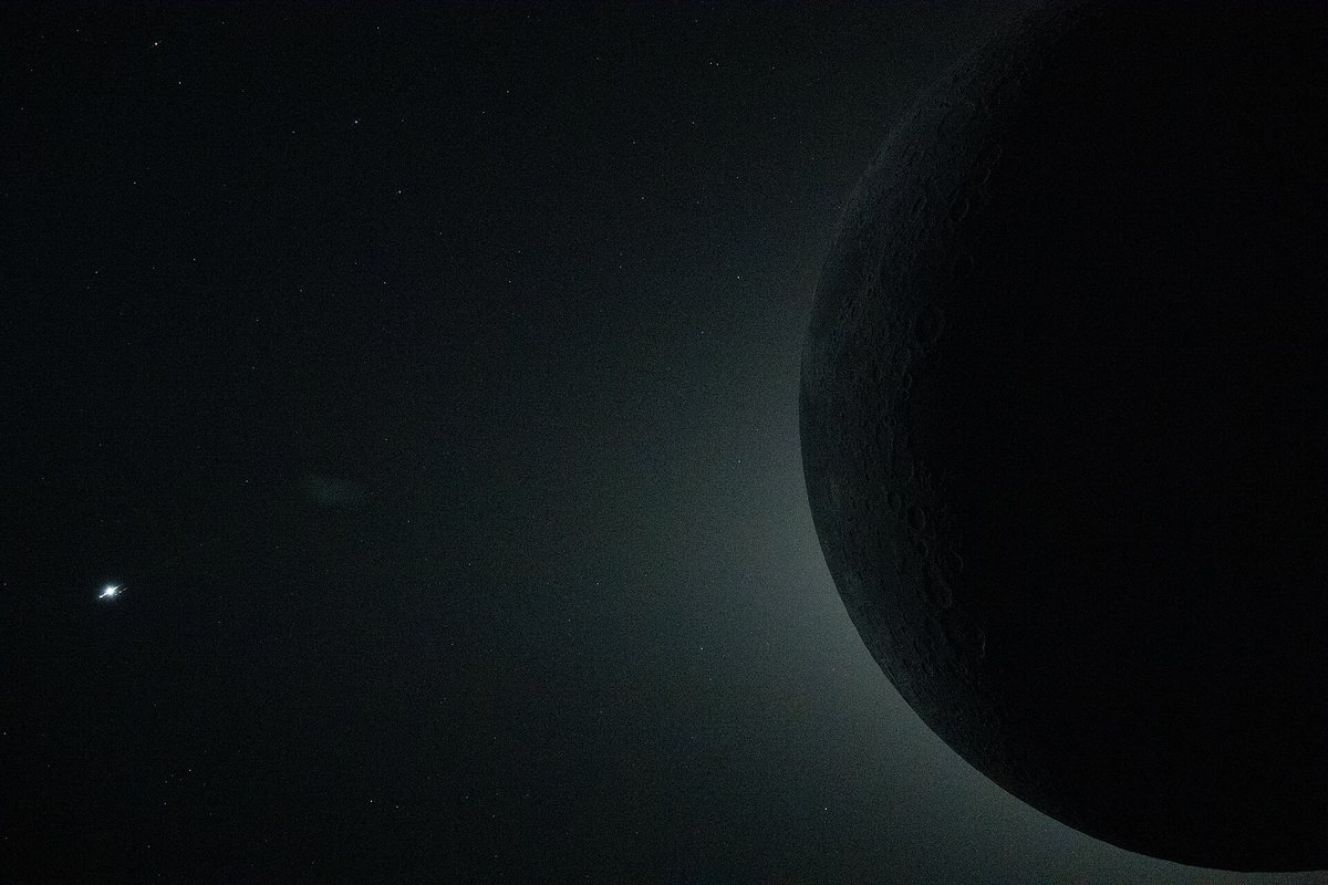 宇宙から見た部分日食の写真。太陽の一部が月に隠れ、明るい光が弧を描いている。