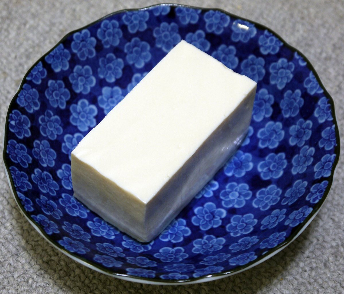 青い花柄の小皿にのった、白い四角い絹ごし豆腐